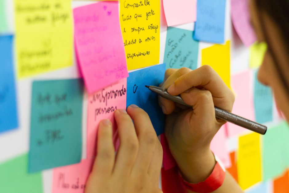 Hands writing on colorful sticky notes during a brainstorming session