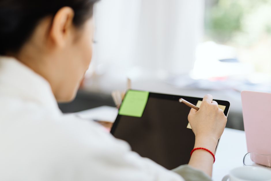 Person using a stylus on a tablet to take notes in a digital planner