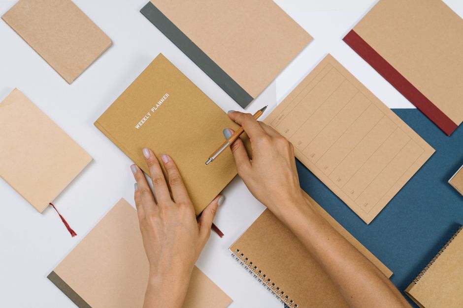 Flat lay of a paper planner and notebook on a desk, representing the physical planner format